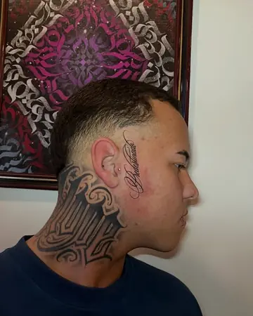 Perfil de um rapaz com lettering gótico grande na nuca e a palavra Predestinado em script perto do olho; ao fundo, uma tela de caligrafite rosa e prata