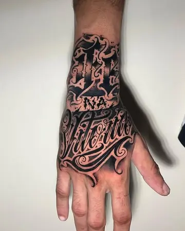 Costas da mão com lettering chicano em preto e cinza, terminando na palavra Vitória