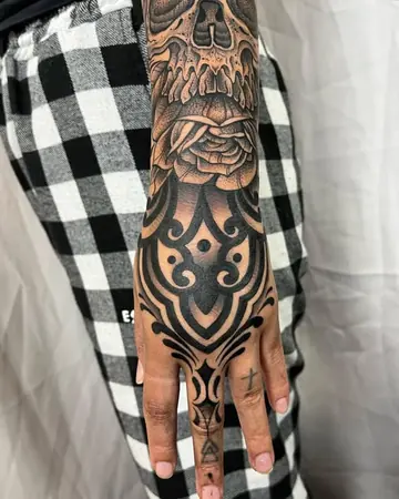 Mão e antebraço com ornamentos em blackwork, uma rosa e uma caveira